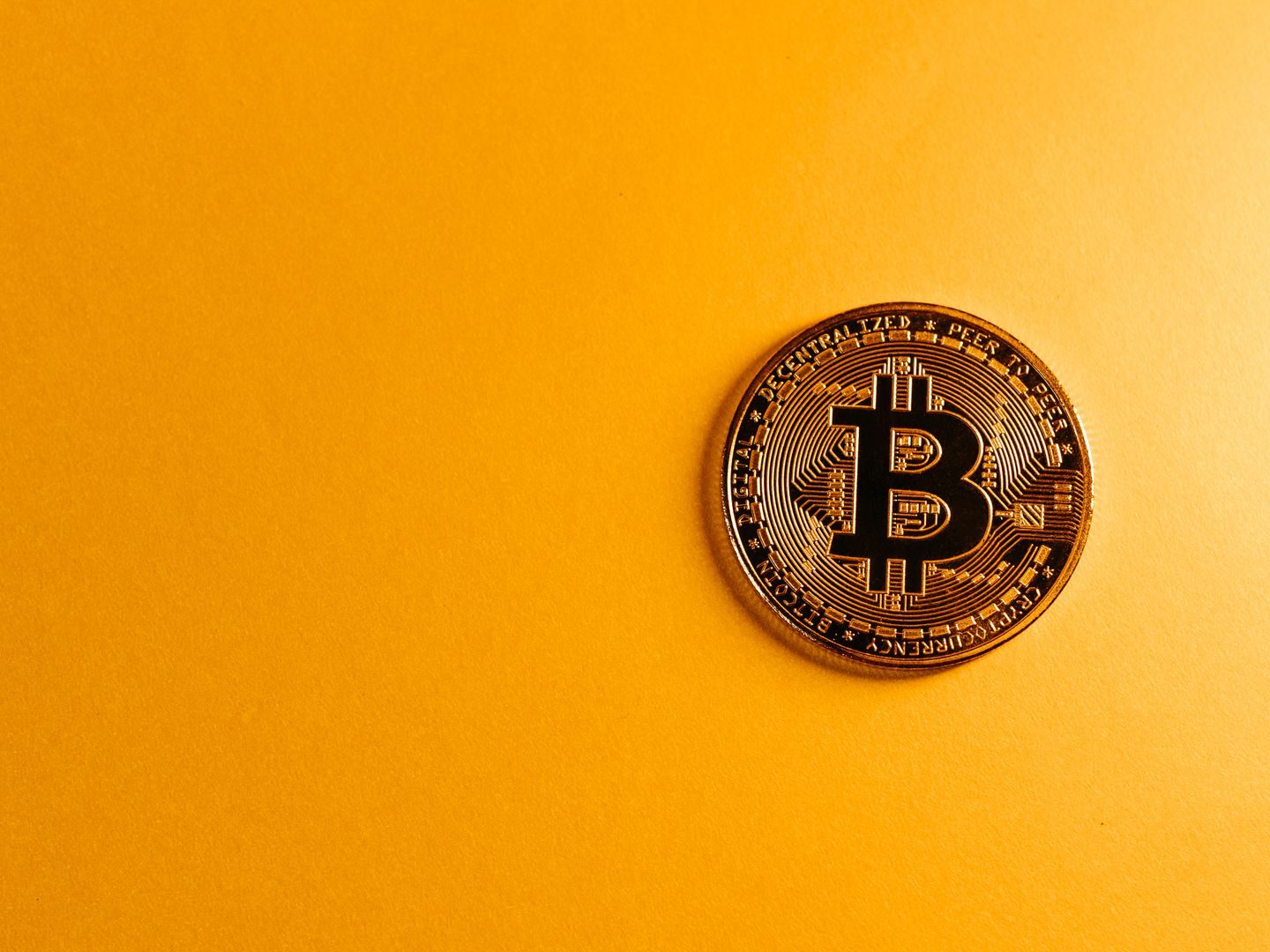 Close up of a Bitcoin cryptocurrency coin on a vibrant yellow background, symbolizing digital money.